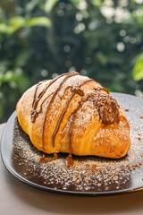 Cornetto artigianale farcito con cioccolato al latte e guarnito con zucchero a velo servito in un bar