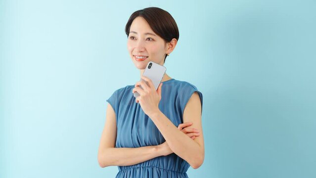 スマートフォンを使うワンピースを着た若い女性	