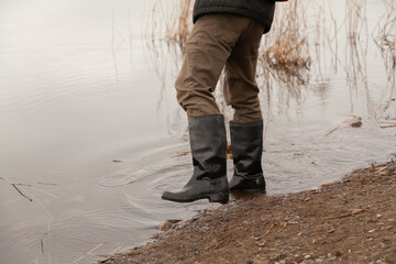 Feet in rubber boots walk along the water edge....