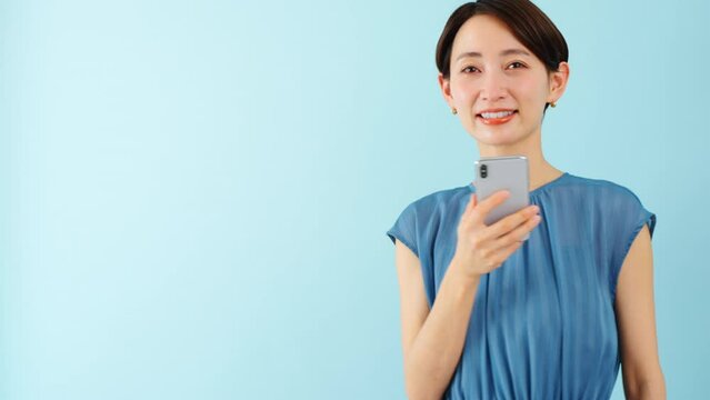 スマートフォンを使うワンピースを着た若い女性	