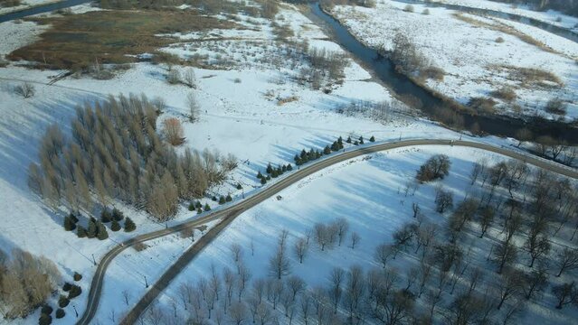 A winding bike path in a city park. City park in winter. Snow lies on the ground. Aerial photography.