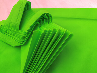 pile of light green porous tote bags. non-woven fabric material. polypropiline bags on wooden planks