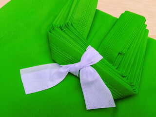 pile of light green porous tote bags. non-woven fabric material tied with white rope. polypropiline...