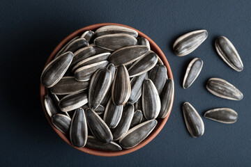 Black sunflower seeds in a bowl on dark background,top view
