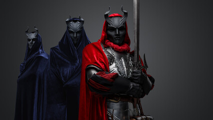 Portrait of mysterious cultists dressed in robes with hood and black horned masks.