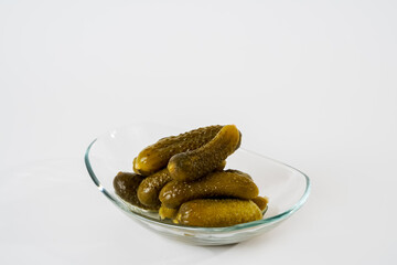 Top view of pickled gherkins on glass plate isolated on white background.