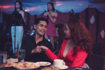 A gentleman gives a shy handshake as he is happy to meet his date for the first time. An Asian man...