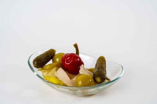Mixed gherkins, sauerkraut, pepper, tomato and cucumber pickles on glass plate isolated on white background.