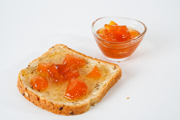 Naklejka na ściany i meble Homemade apricot jam, small bowl and a slice of bread with jam isolated on white background.