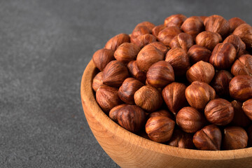 View of a bowl full of hazelnuts on a black background
