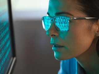 Close-up of programmer with binary code reflected in eyeglasses
