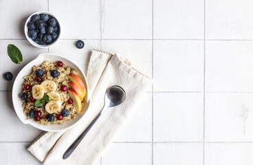 Oatmeal with apple, banana, blueberry, cranberry and mint on the white background. Copyspace.
