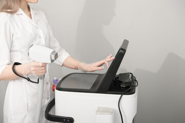 woman wearing white medical uniform holding laser epilation machine device. beauty and skincare...