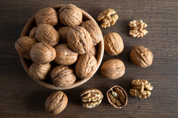 Peeled walnuts and whole walnuts in wooden bowl

