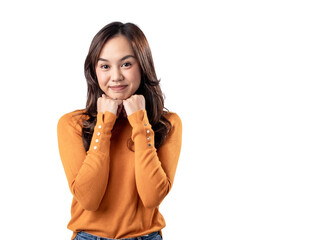 A portrait of a happy Asian Indonesian woman wearing an orange sweater and clenching both hands under her chin, isolated on a white background