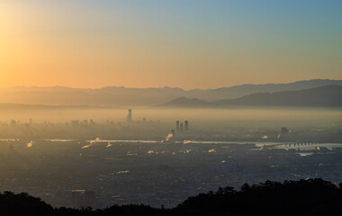 Orange sunrise glow and blue sky with smog layer over city skyscrapers 