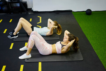 Young fit sporty women doing abdomen exercises on mats