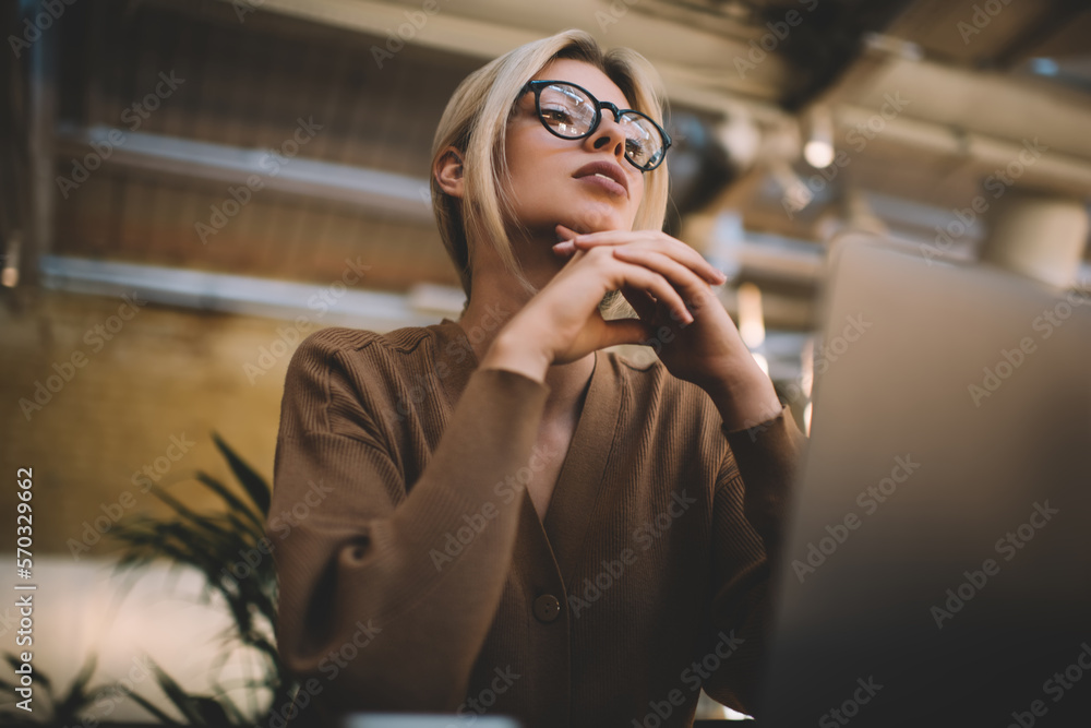 Poster pondering female blogger in classic spectacles thinking about web design for wireless page during re