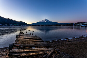 The wooden bridge over lake of Kawaguchiko are frozen in January with Mt. Fuji in background.