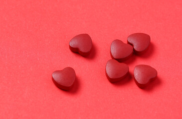 red heart-shaped coenzyme Q10 tablets placed on a red background