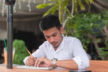 A graphic artist checks the time on his wristwatch as he scribbles on his sketchpad with his pencil.