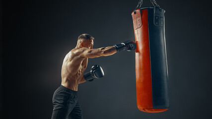 Boxer at the moment of impact on punching bag over black background