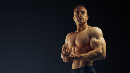 Focus on arms and fists of handsome athlete bodybuilder. Muscular arms of a young attractive guy....