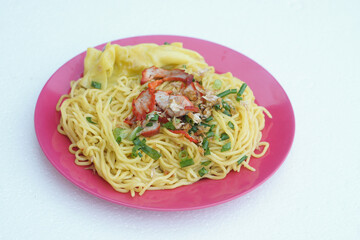 Selective focus on stir fried yellow noodle with pork and vegetables on dish, white  background. Concept, traditional food, delicious, easy to cook or can order from Thai restarant of street food     