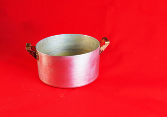An old aluminum pan made in circa 1960 against a red background.