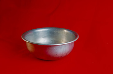 An old aluminum bowl made in circa 1960 against a red background.