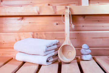 Detail of white towels, wooden spoon and stones in a sauna, wellness accessories.