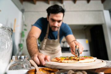 handsome chef cut delicious homemade italian mozzarella pizza after prepare and bake from stove or oven for lunch meal or dinner in local italian pizza restaurant