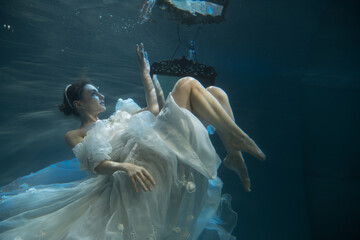 Young woman in wedding dress under water