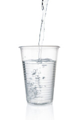 Flowing pure water into disposable plastic cup on white background