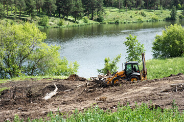 tractor works in the park for landscaping next to the river