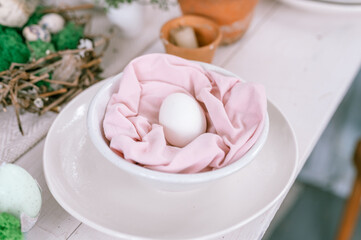 happy easter holiday in springtime season. festive home decor. traditional food. natural white chicken egg in pastel pink fabric in a plate on the table