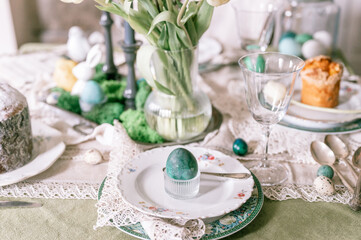 happy easter holiday in springtime season. painted green emerald colored chicken egg in bowl and plate on table. festive home decor. traditional food. sophisticated country rustic tablescape style