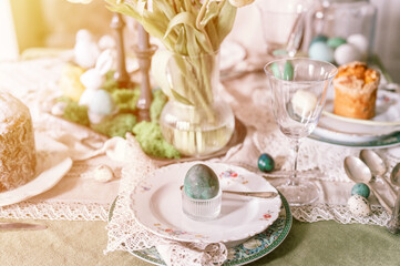 Fototapeta na wymiar happy easter holiday in springtime. painted green emerald colored chicken egg in bowl and plate on table. festive home decor. traditional food. sophisticated country rustic tablescape style. flare