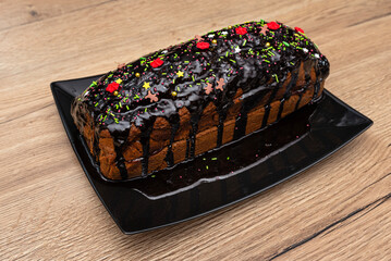 Gingerbread cake with chocolate icing and jam inside, sprinkled with sweet decorations on top.