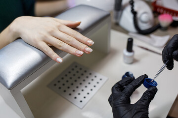 The work of the manicurist in the salon. Coating transparent base shellac nails. Beauty and hand care concept.