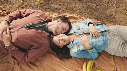 Young couple lying on blanket in the park. View from above