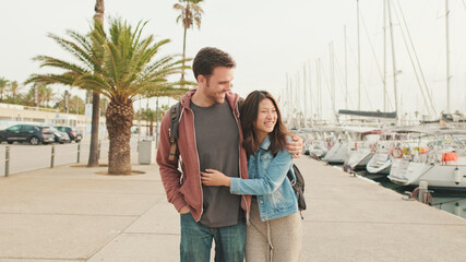 Fototapeta na wymiar Young happy couple walking hugging along the promenade