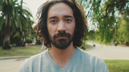 Close up, young man raises his head, looks at the camera and smiles