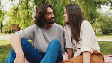 Fototapeta premium Happy smiling couple talking while sitting on blanket in park. Close-up