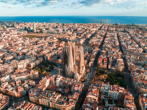Aerial view of Barcelona City Skyline and Sagrada Familia Cathedral at sunset. Eixample residential famous urban grid. Cityscape with typical urban octagon blocks