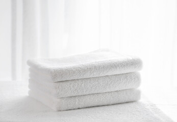 Fototapeta na wymiar Three white terry bath towels on a light background in the bathroom
