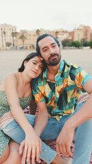 Obraz premium Happy couple sitting hugging on blanket on the beach
