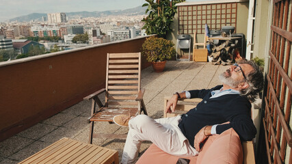 Middle-aged man enjoying sunny weather on the balcony
