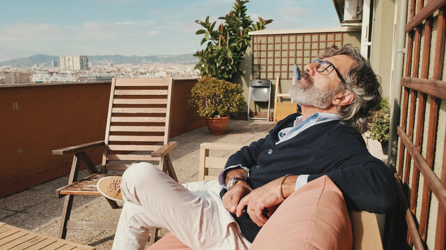 Middle-aged man enjoying sunny weather on the balcony
