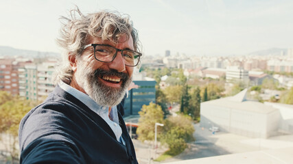 Close-up of mature man taking selfie while standing on balcony, looks at camera